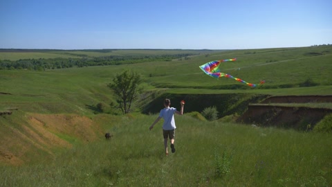 一个十几岁的男孩手里拿着风筝在风中奔跑。活跃的孩子视频素材模板下载