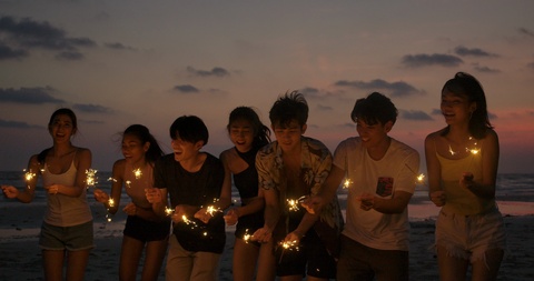年轻的青少年在沙滩上手持火花棒