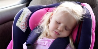 睡在婴儿汽车座椅上的小女孩。