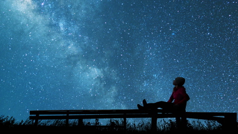 女孩在郊外的座椅上看着夜空中的星星视频素材模板下载
