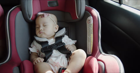 在家庭公路旅行中，快乐的亚洲婴儿睡在汽车座椅上。