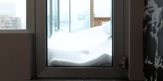 一个拿着铲子的男人站在窗户前等待雪。带着
