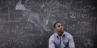 坐在黑板前思数学公式的男人
