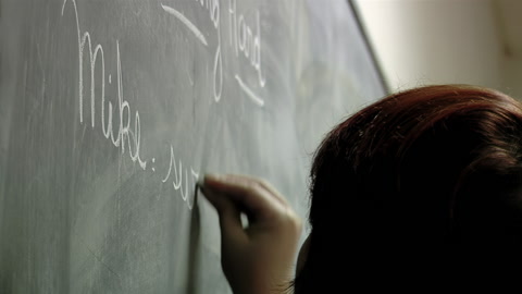 女教师在课堂英语课上用黑板写字。 视频素材模板下载