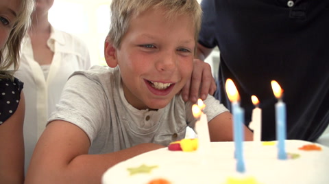 男孩吹灭蛋糕上蜡烛的慢动作序列视频素材模板下载