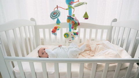 婴儿在白色木制的婴儿床里玩玩具