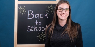回到学校，一名戴眼镜的女教师站在学校黑板旁边