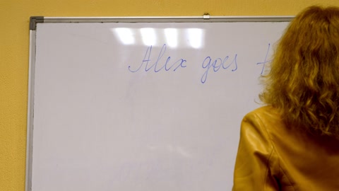 老年女教师在黑板上写字，背景是教室