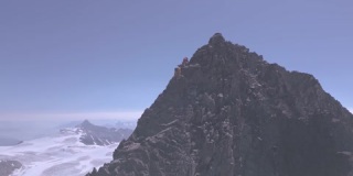山顶山脊上的登山者接近有冰川的高海拔山峰