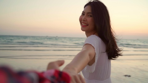 慢动作——年轻的亚洲夫妇在海滩上跑步和玩耍。