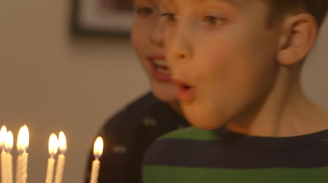 年轻男孩试图吹灭他生日蛋糕上的所有蜡烛视频素材模板下载