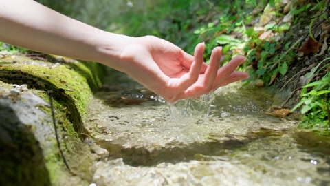 手触摸流动的溪流水