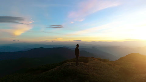 站在山顶上的男人看着美丽的日出