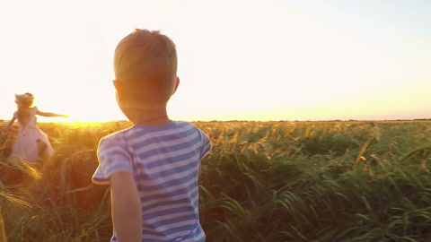 日落时分两个孩子在田野里奔跑