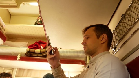 一个人在客运列车的车厢里使用智能手机。4k视频素材模板下载