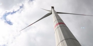 一个现代风力涡轮机在多云的天空前旋转4k30fps视频