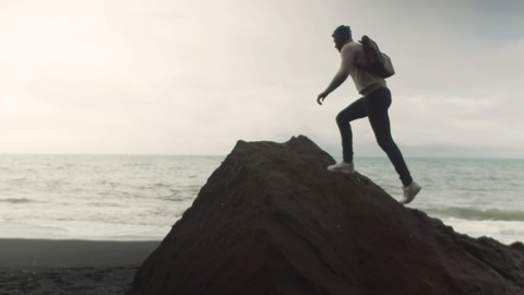年轻游客在雷尼斯夫哈拉海滩跳下一块黑色岩石视频素材模板下载
