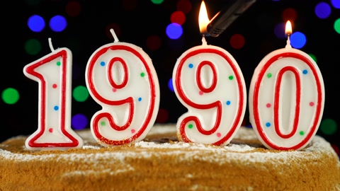 以数字1990的形式，带有白色燃烧蜡烛的生日蛋糕视频素材模板下载