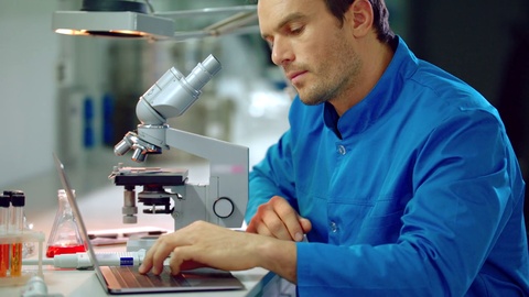 男性科学家在实验室看显微镜。显微镜实验室研究视频素材模板下载