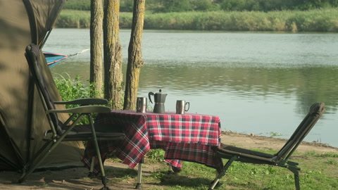 钓鲤鱼的早晨。河岸上的露营帐篷、桌椅视频素材模板下载