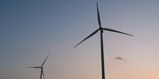 能源，风力发电机剪影在日落时分映衬在蓝天下，洁净环保