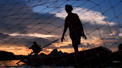 日落时渔民投掷渔网的慢动作剪影
