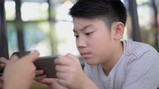  00:01|00:10 1×亚洲男孩从智能手机玩游戏。视频素材模板下载