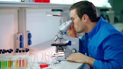 男性科学家在进行显微镜研究男性科学家正在看显微镜视频素材模板下载