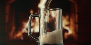 黑暗中火背景上的啤酒。棕色玻璃上的火焰游戏。慢动作