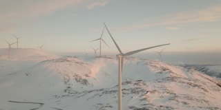 在雪山上缓慢旋转的风力涡轮机；北极圈的绿色能源