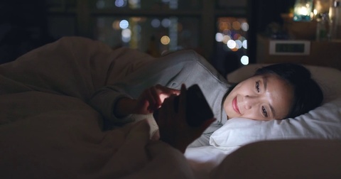 女人躺在床上看手机