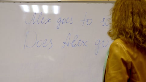 老年女教师在黑板上写字，背景是教室视频素材模板下载