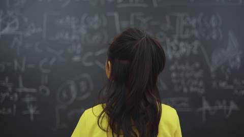 一个女人正在研究黑板上的问题视频素材模板下载
