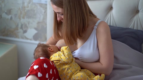 母亲在卧室床上喂新生婴儿母乳视频素材模板下载