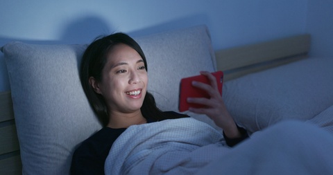 夜晚躺在床上看手机的女子