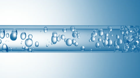 特写透明液体在玻璃管中流动的不同大的气泡