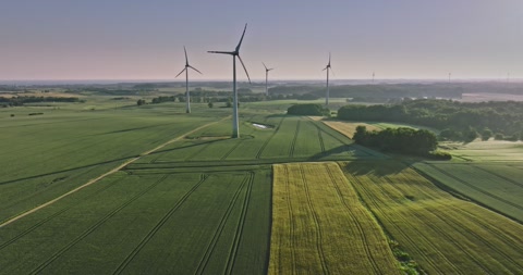 日出时风力涡轮机和绿地的鸟瞰图