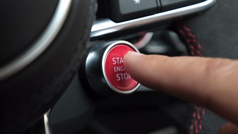 手指在一辆运动车中按下发动机启动按钮的特写镜头