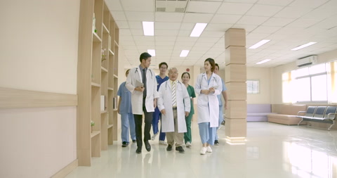 亚洲医生和资深医生在医院散步交谈