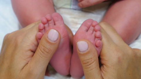 新生婴儿的小脚在母亲手中。婴儿的脚在父母手中。快乐视频素材模板下载