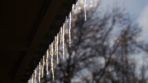 冬天屋顶上的冰柱在春天的阳光下融化，从中滴落下来