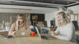 两名女性戴着耳机，同时看着笔记本电脑并进行交谈，她们是女性客服人员高清在线视频素材下载