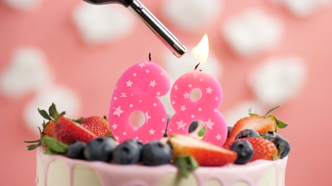 68号生日蛋糕蜡烛。蜡烛和蛋糕在粉色背景和火视频素材模板下载