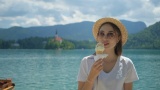 女旅行者正在布莱德湖海岸的度假区吃冰淇淋高清在线视频素材下载