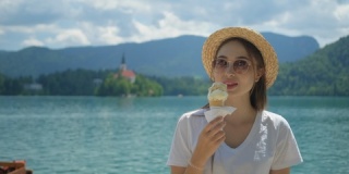 女旅行者正在布莱德湖海岸的度假区吃冰淇淋
