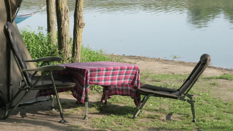 钓鲤鱼的早晨。河岸上的露营帐篷、桌椅视频素材模板下载