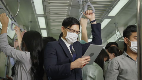 亚洲商人乘坐轻轨上班时戴口罩的视频