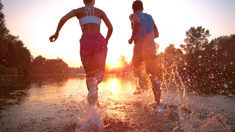 训练伙伴在日落前清爽的河水中跑步
