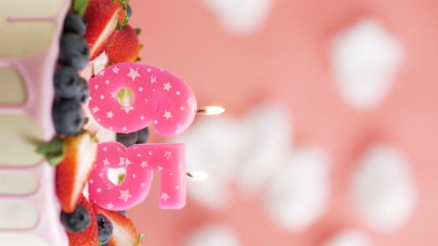 65号生日蛋糕蜡烛。粉色蜡烛和蛋糕的垂直视频视频素材模板下载