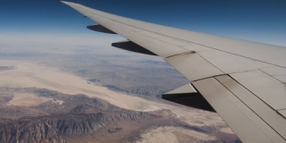 从飞机窗户上方以飞行高度观赏岩石构造的翼和沙漠景象